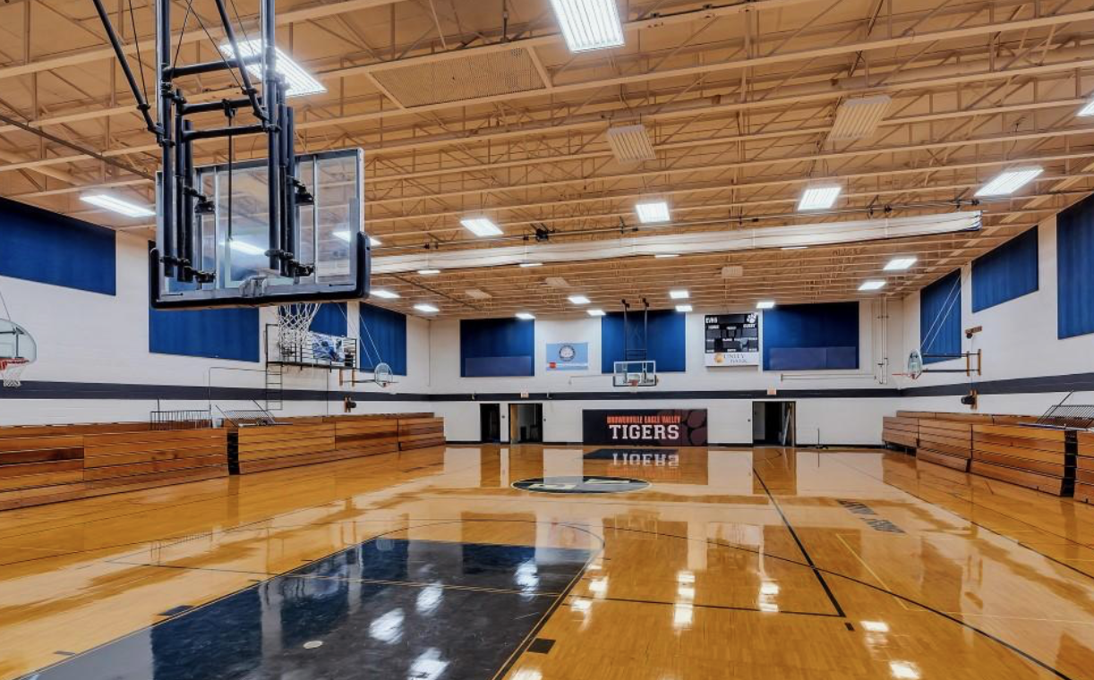 Full-size gymnasium with hardwood court and bleachers